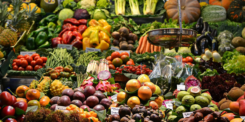 Fresh fruit and vegetables stacked on a greengrocer's display with price labels