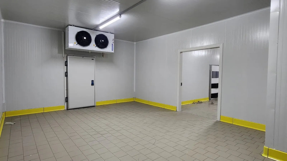 Inside a newly built cold room with a twin-fan evaporator, white insulated panels and a hinged door