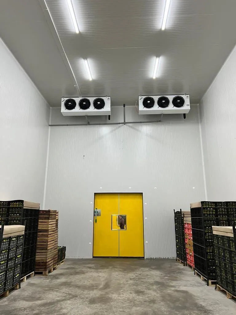 Cold store with pallets of fruit and vegetable crates either side of a yellow double door