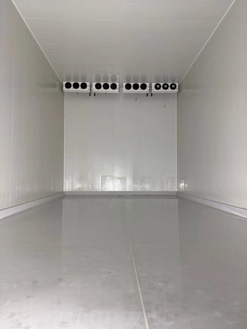 Empty walk-in freezer room with four evaporators on the back wall and a smooth insulated floor