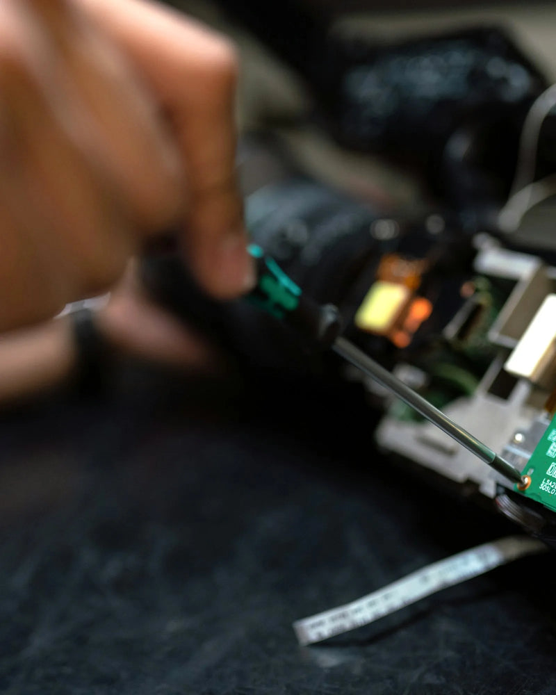 Engineer's hand using a screwdriver on an electronic control board during a repair